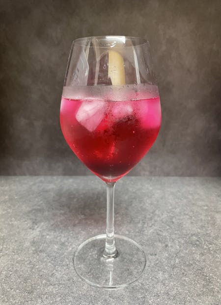 ワイングラスにしそジュースの氷を入れ、炭酸水を注いだ様子。