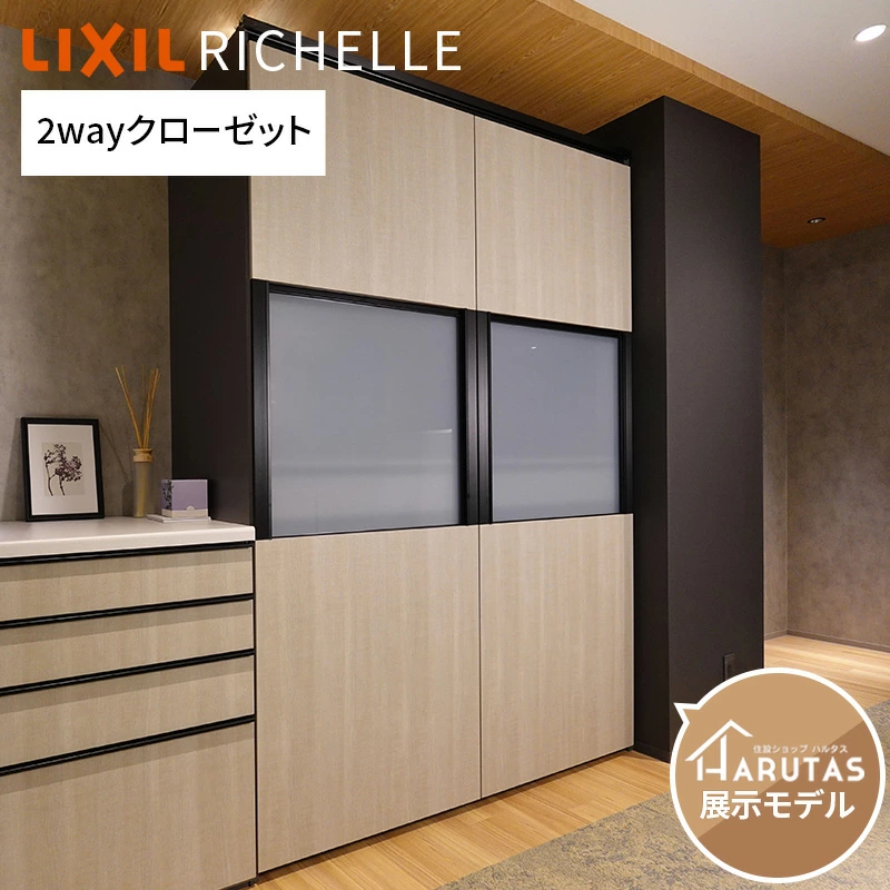 「LIXIL RICHELLE 2wayクローゼット」の文字。木目調の大容量収納キャビネットが天井まで設置され、上部と下部は木目扉、中央に半透明のグレーガラス扉が2枚配置されている。左側には木目調の引き出し収納と、花瓶や写真立てが飾られた白いカウンターがある。右下に「HARUTAS展示モデル」の丸いロゴマークが表示されている。