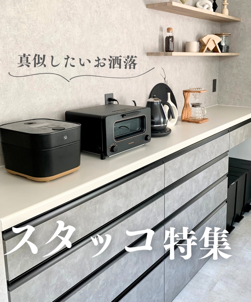 グレー系のキッチンカウンター収納。黒い炊飯器やオーブントースター、電気ケトル、木製ドリッパースタンドが並び、上部の飾り棚にはコーヒー豆瓶やカップなどが置かれている。文字で「真似したいお洒落」「スタッコ特集」と書かれており、収納棚のカラーバリエーションを紹介する画像。