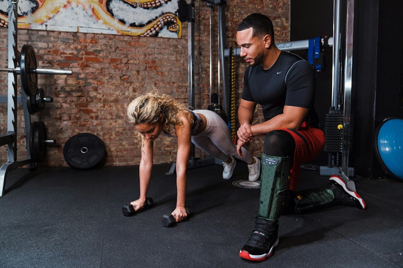 A personal trainer guiding a man through push-ups – showcasing the top personal training benefits for a healthier lifestyle.