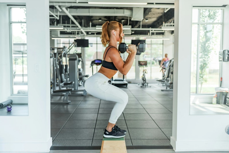 Beginner woman lifting dumbbells during a personal training session, representing a sample workout plan