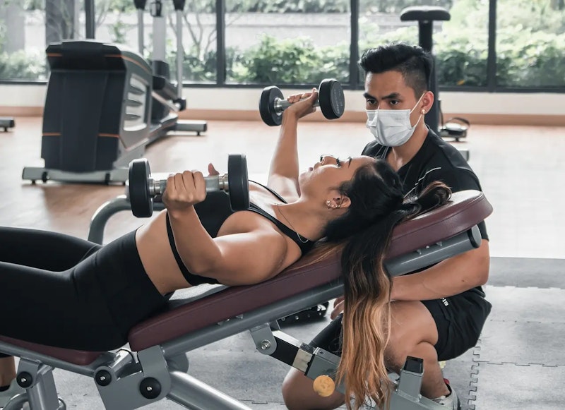 A woman training at the gym with a personal trainer – illustrating the benefit of choosing the right personal trainer for motivation, support, and results.