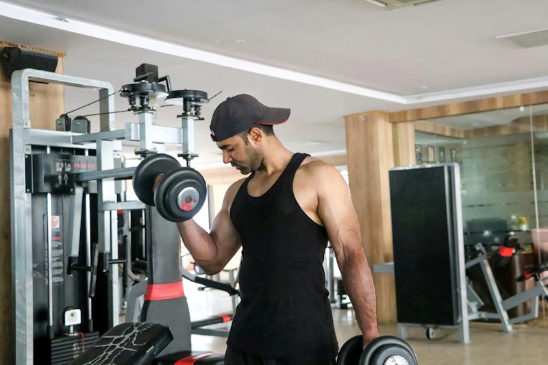 A personal trainer guiding a man lifting dumbbells at the gym – representing the core benefit of personal training: expert support tailored to your goals.