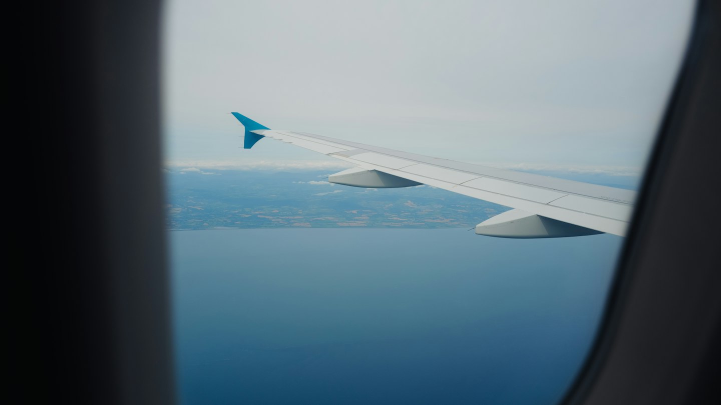 飛行機の翼と眼下に広がる青い海