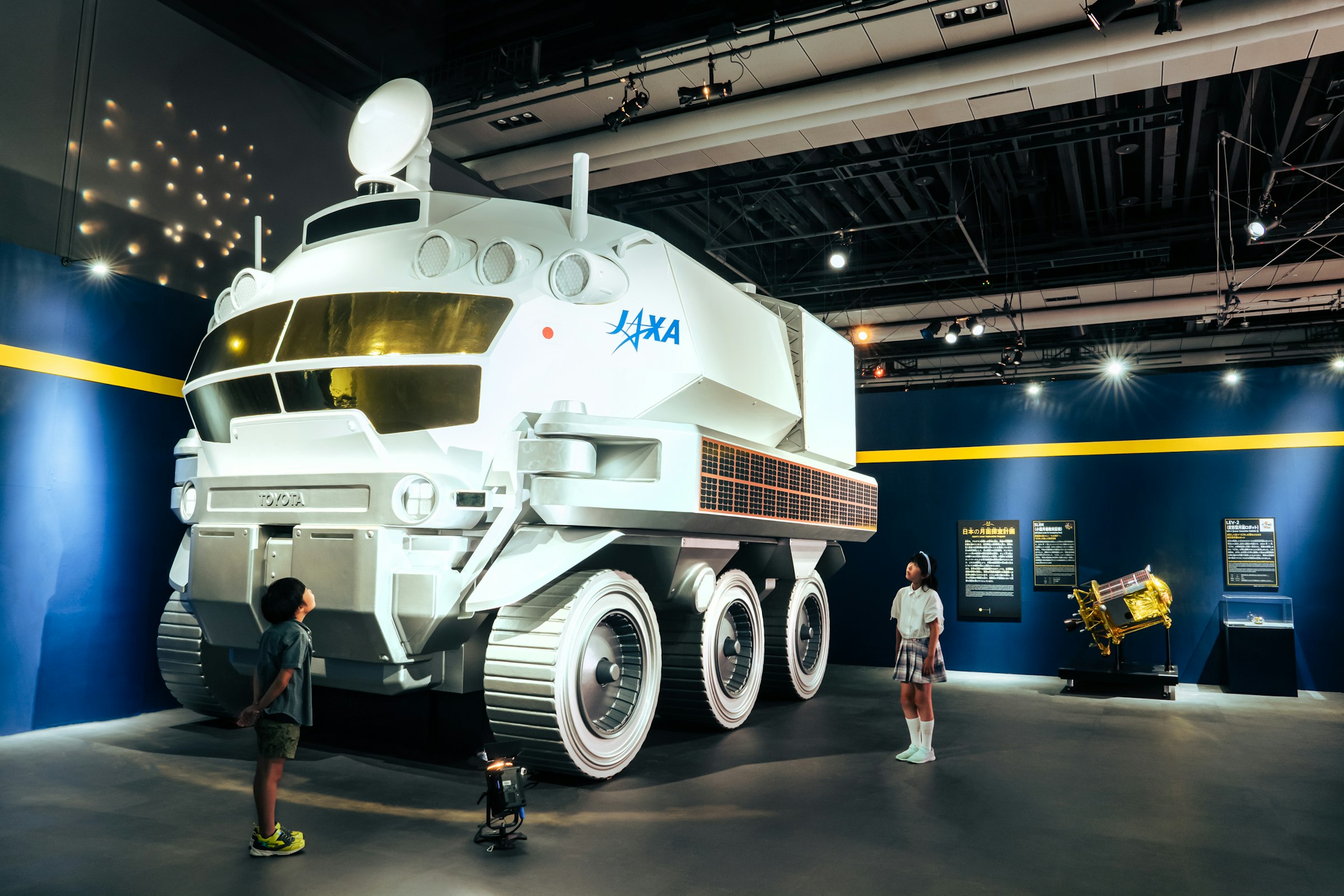 有人月面探査車「有人与圧ローバー」実物大模型（※特別展「深宇宙展」展示風景）。日本は現在、宇宙服を着ずに車内で1年のうち約1ヶ月間、月面を移動・生活できる有人月面探査車の研究開発を（JAXA・トヨタ自動車などが）進めている。有人与圧ローバーの開発で培われた技術が、将来的に日本独自の宇宙服開発へと繋がるかもしれない