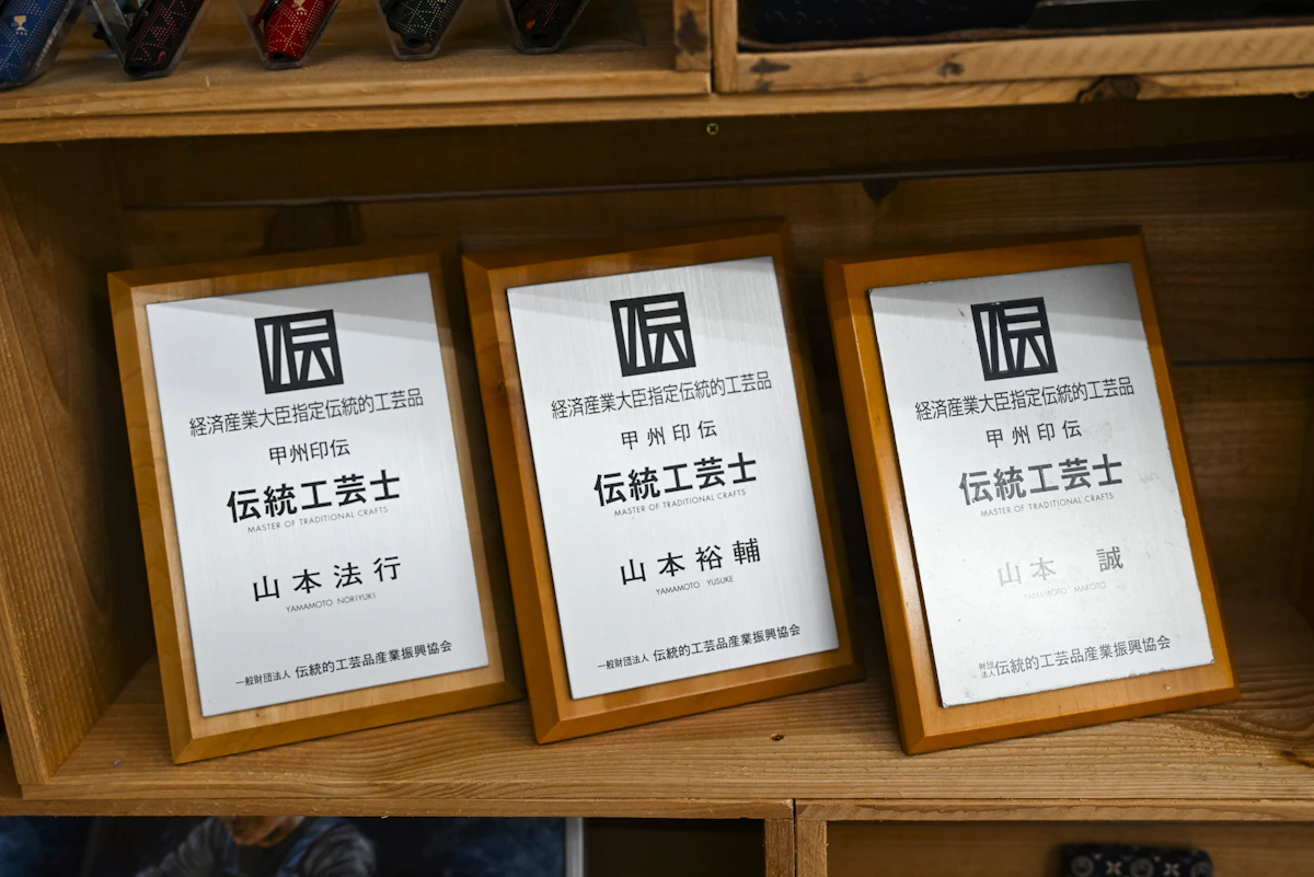 「印伝の山本」店舗に並ぶ伝統工芸士の盾。現在では弟の山本法行さんも伝統工芸士に認定された。