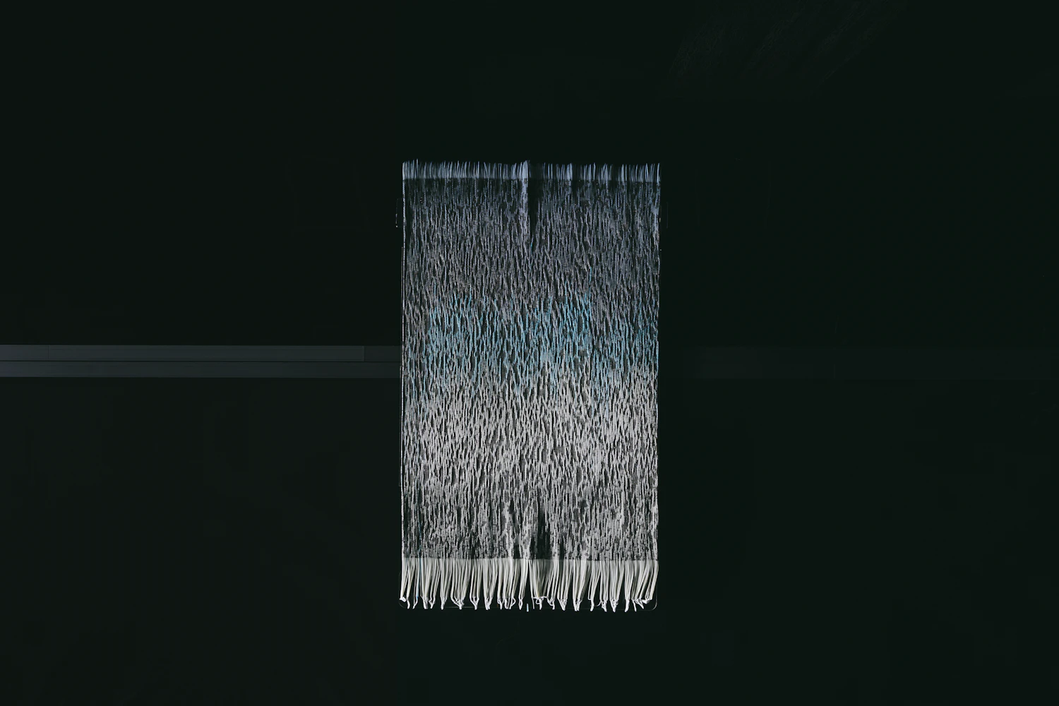 By weaving a unique tube into the warp of the fabric, and letting water dyed with color seep into the tube, the colour changes in 'Drifting Colors.' This is one of the works in 'Ambient Weaving'