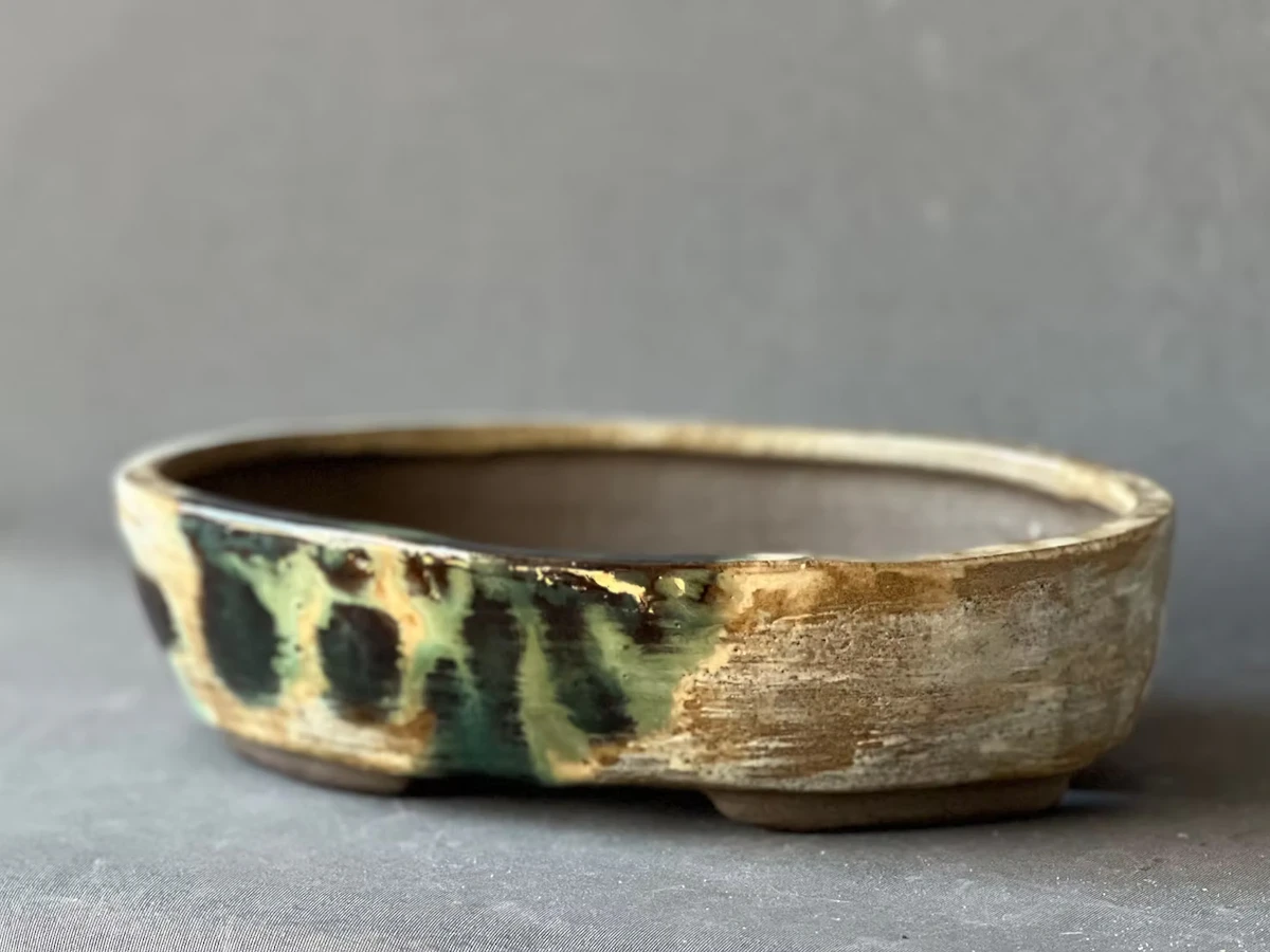 Title: Thor Holvila 2604-07. A bonsai pot glazed to resemble the shadows of branches and twigs, as if reflecting the leaves of a tree after it has been planted.