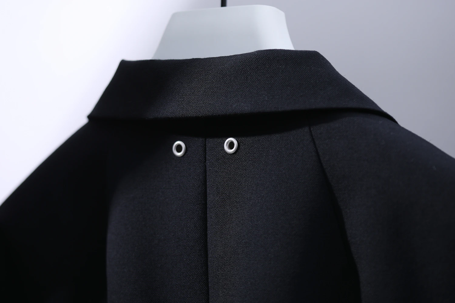 Eyelet embellishments are placed on the back collar of the jacket