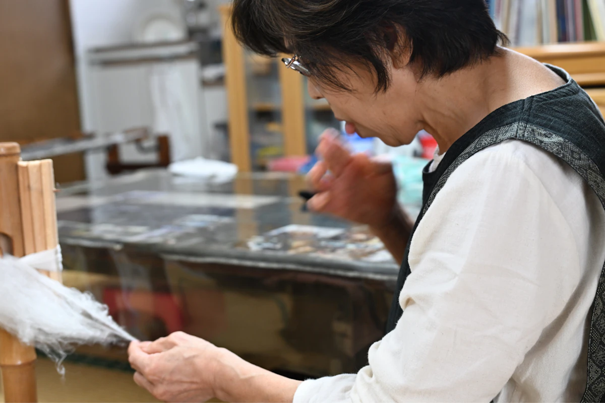 唾液をつけることで、繊維を結合させ、糸をつむいでいく。<br>画像協力：奥順株式会社