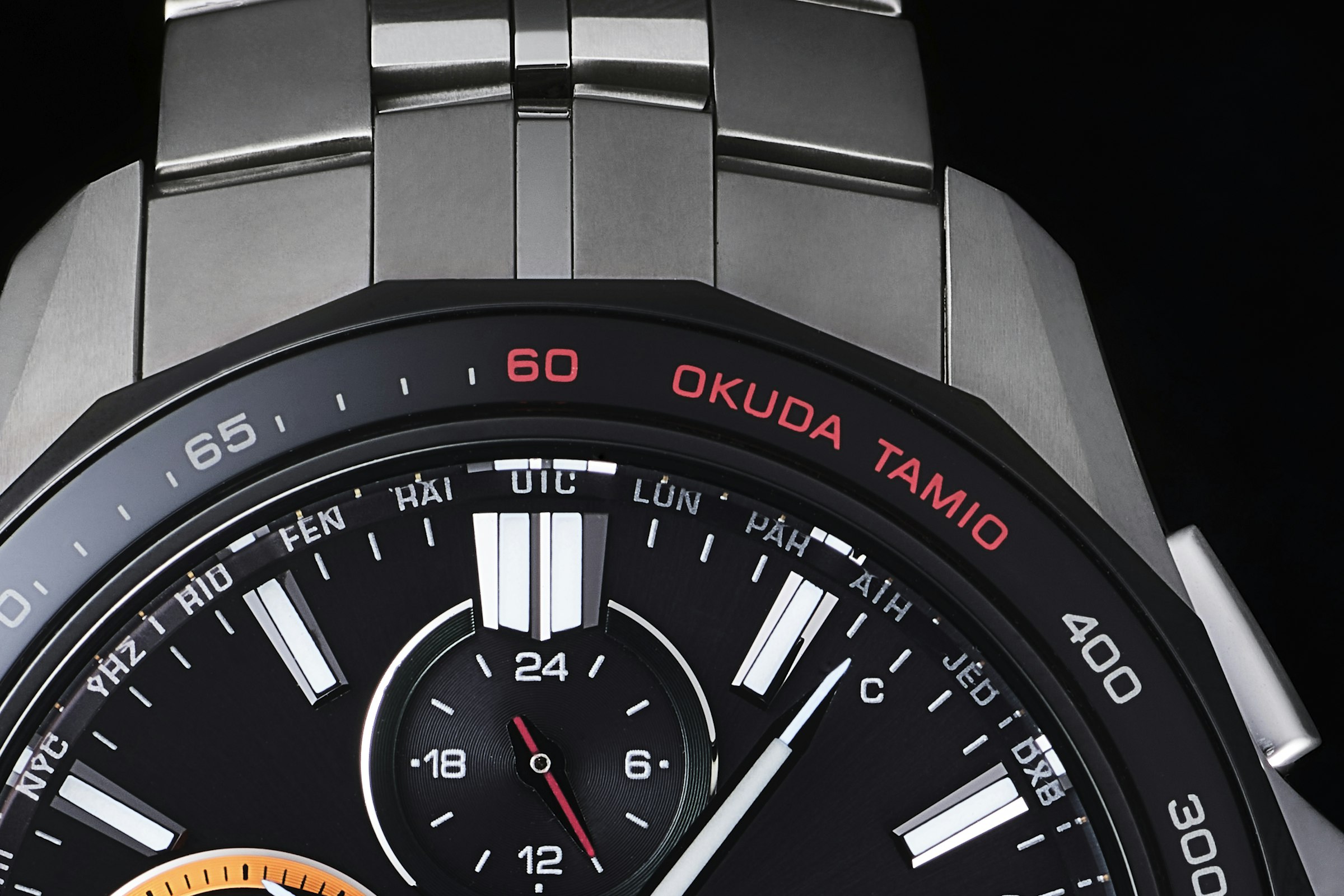ベゼルの12時位置は還暦の60を赤で表現。また通常はTACHYMETERとなる刻印をOKUDA TAMIOに変えているのも面白い
