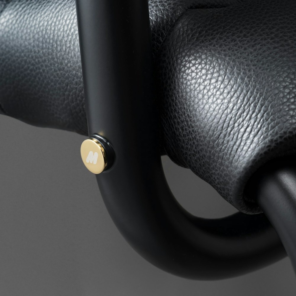 <p>オーバーサイズの黒色メタルフレームを採用し、真鍮製“M”ロゴキャップと手縫いレザーヘムが特徴。シートカバーは調整・交換が可能でメンテナンス性も高い。</p>