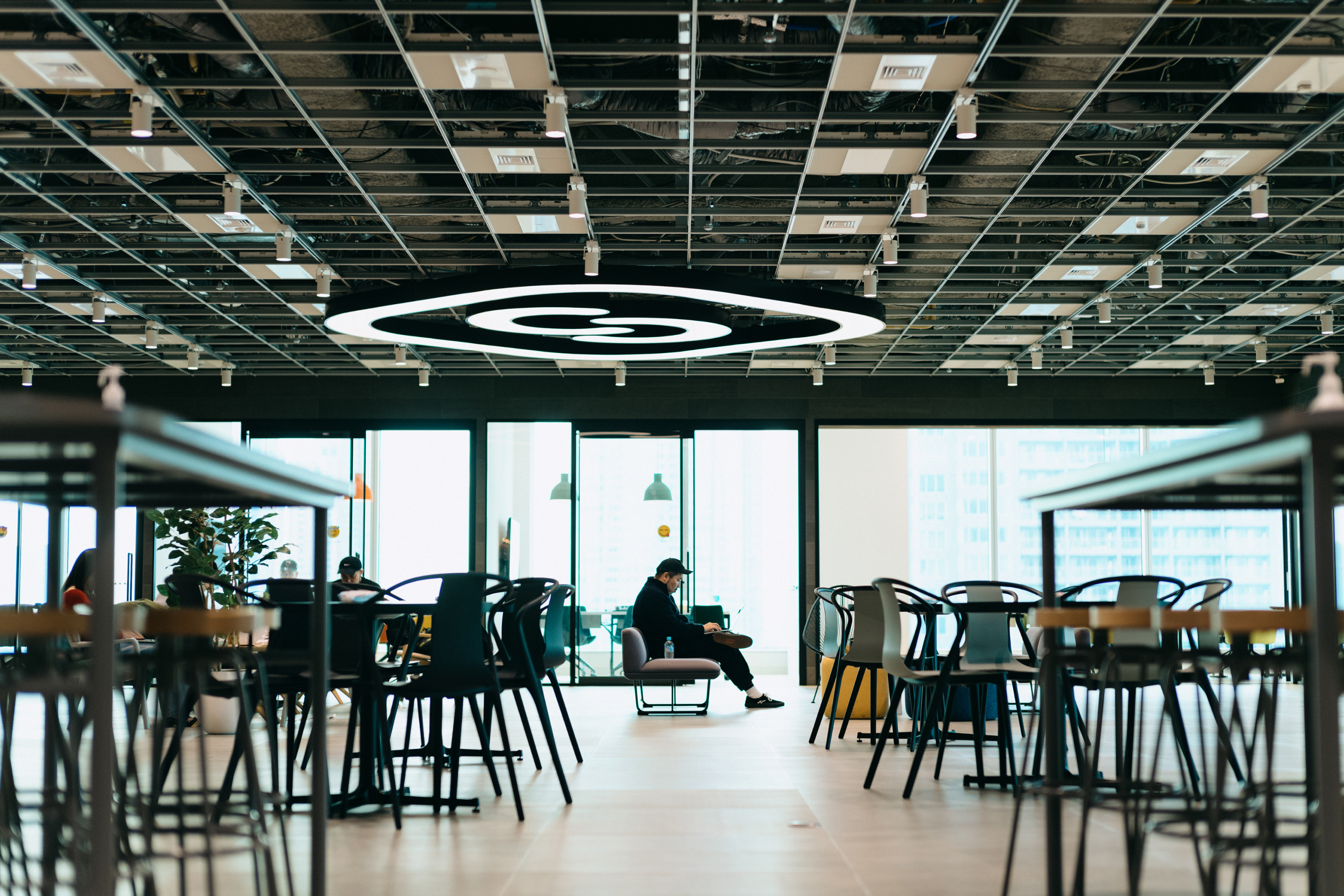 広いフリースペースの一角で作業をする社員。天井に大きなSmartHRのロゴ