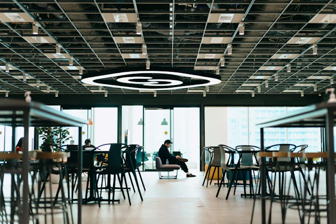 広いフリースペースの一角で作業をする社員。天井に大きなSmartHRのロゴ