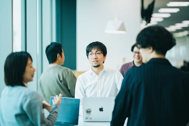 打ち合わせエリアで立って打ち合わせをする2組の社員