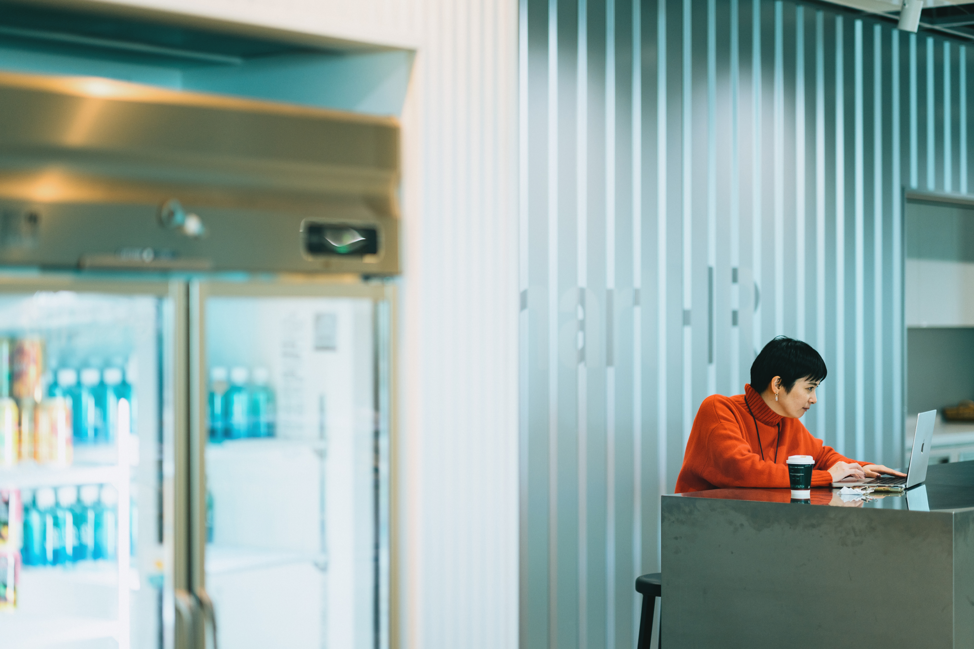 オフィスの冷蔵庫ショーケース前のテーブルで働く社員の写真