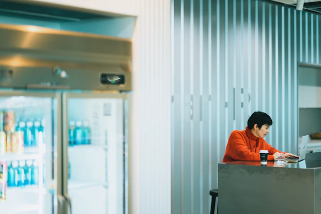 オフィスの冷蔵庫ショーケース前のテーブルで働く社員の写真