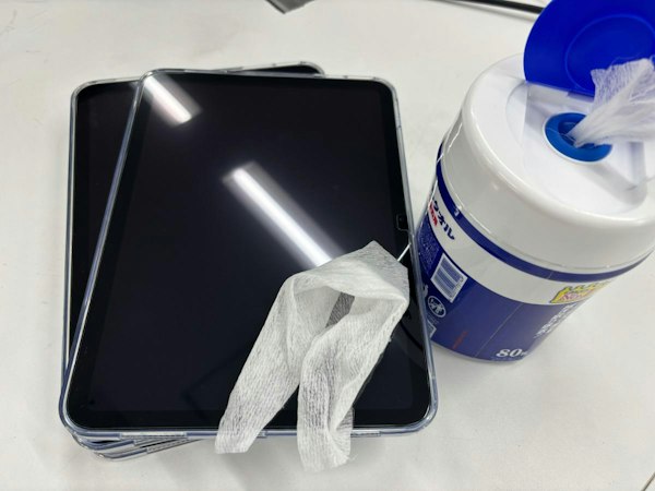 レンタル前後のiPadを専用クロスとアルコールで丁寧に消毒・クリーニングし、品質と衛生状態を保つメンテナンス作業の様子