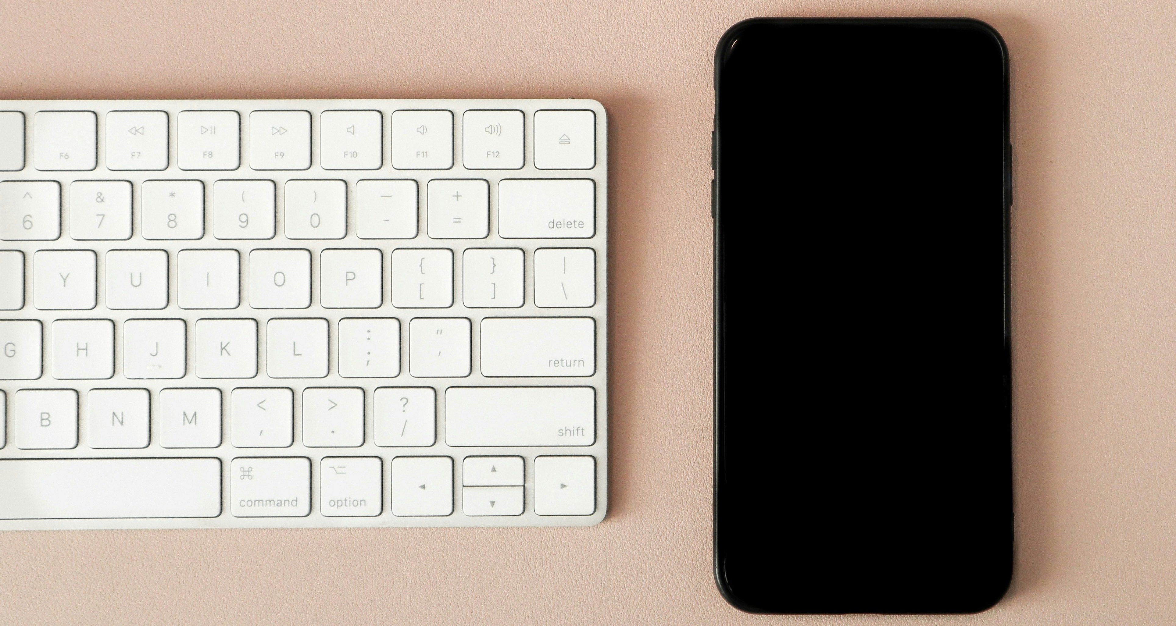 ホームボタン付きiPhoneとキーボード・ヘッドフォンのデスク作業シーン
