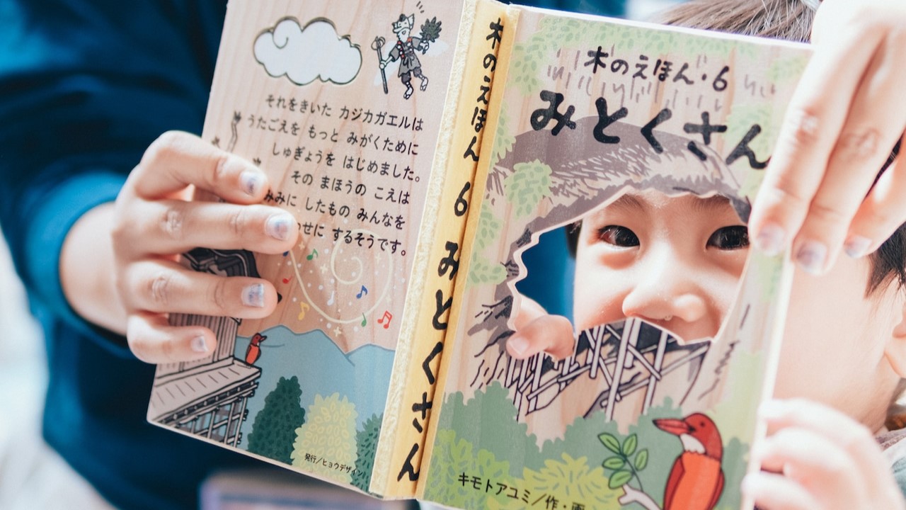 木のえほんを読んで楽しんでいる子どもの画像