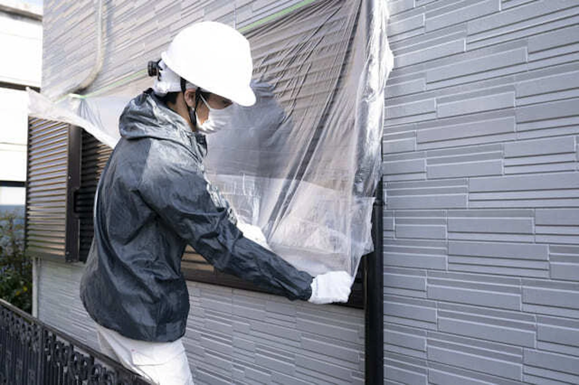 住宅の窓を養生する塗装職人の写真