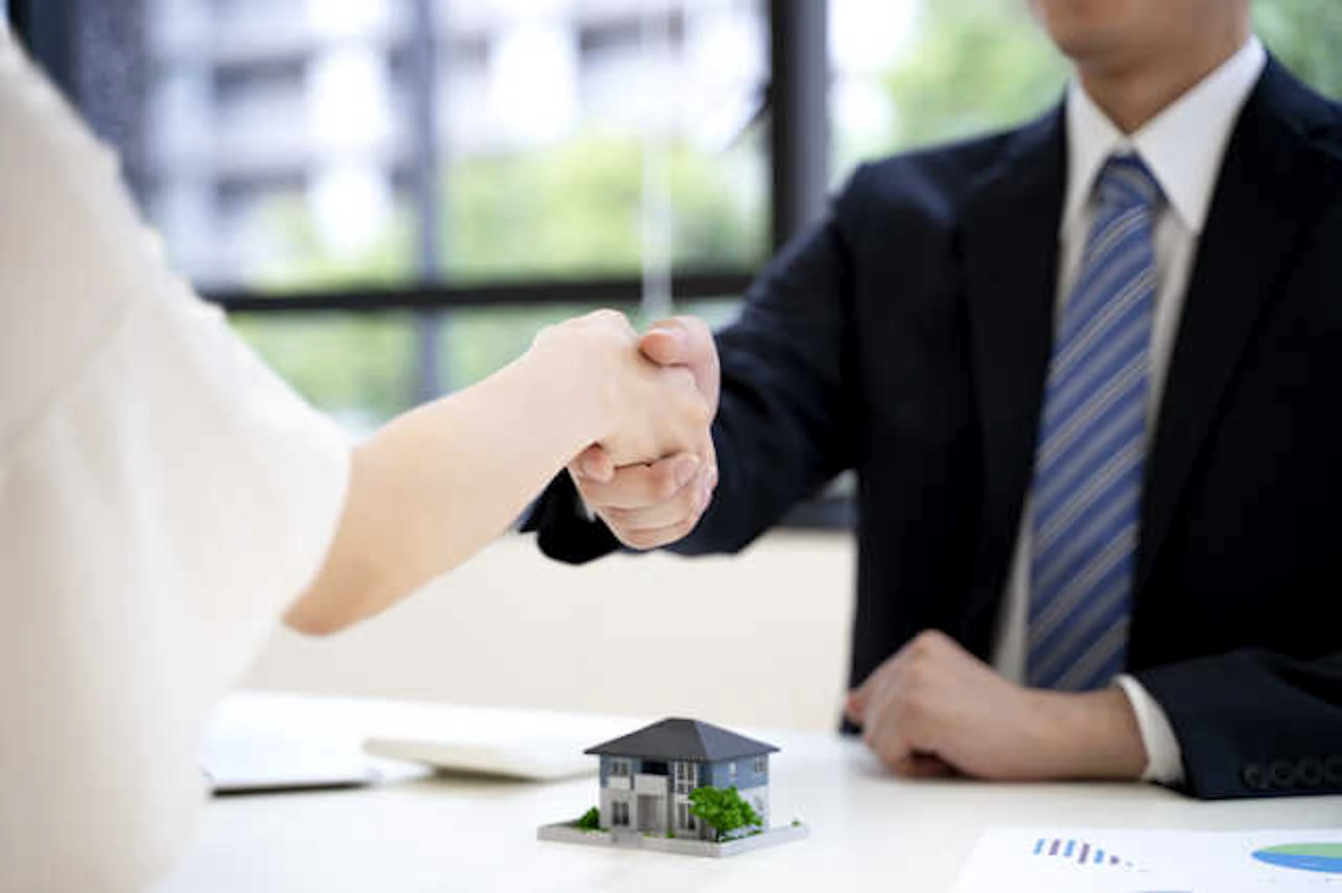 机の上で握手を交わすスーツを着た男性と白い服の女性