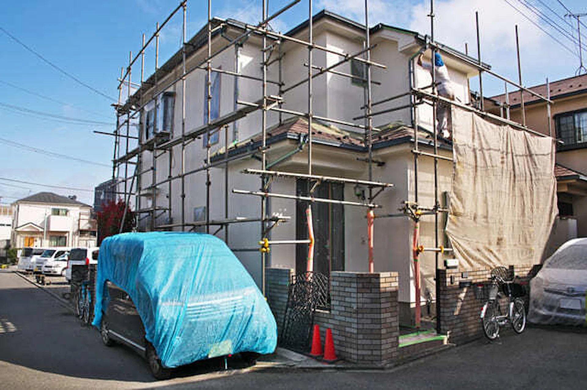 塗料飛散防止ネットがかけられた外壁塗装工事の現場写真