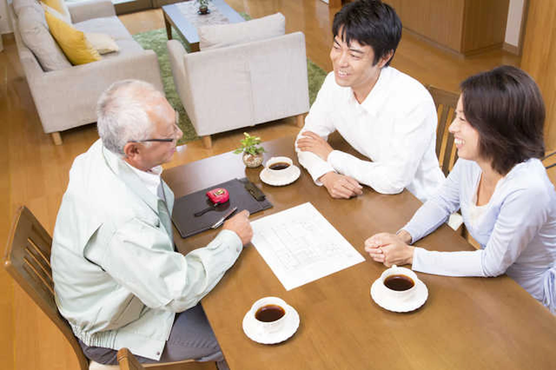 楽しそうに会話するリフォーム業者の男性と若い夫婦