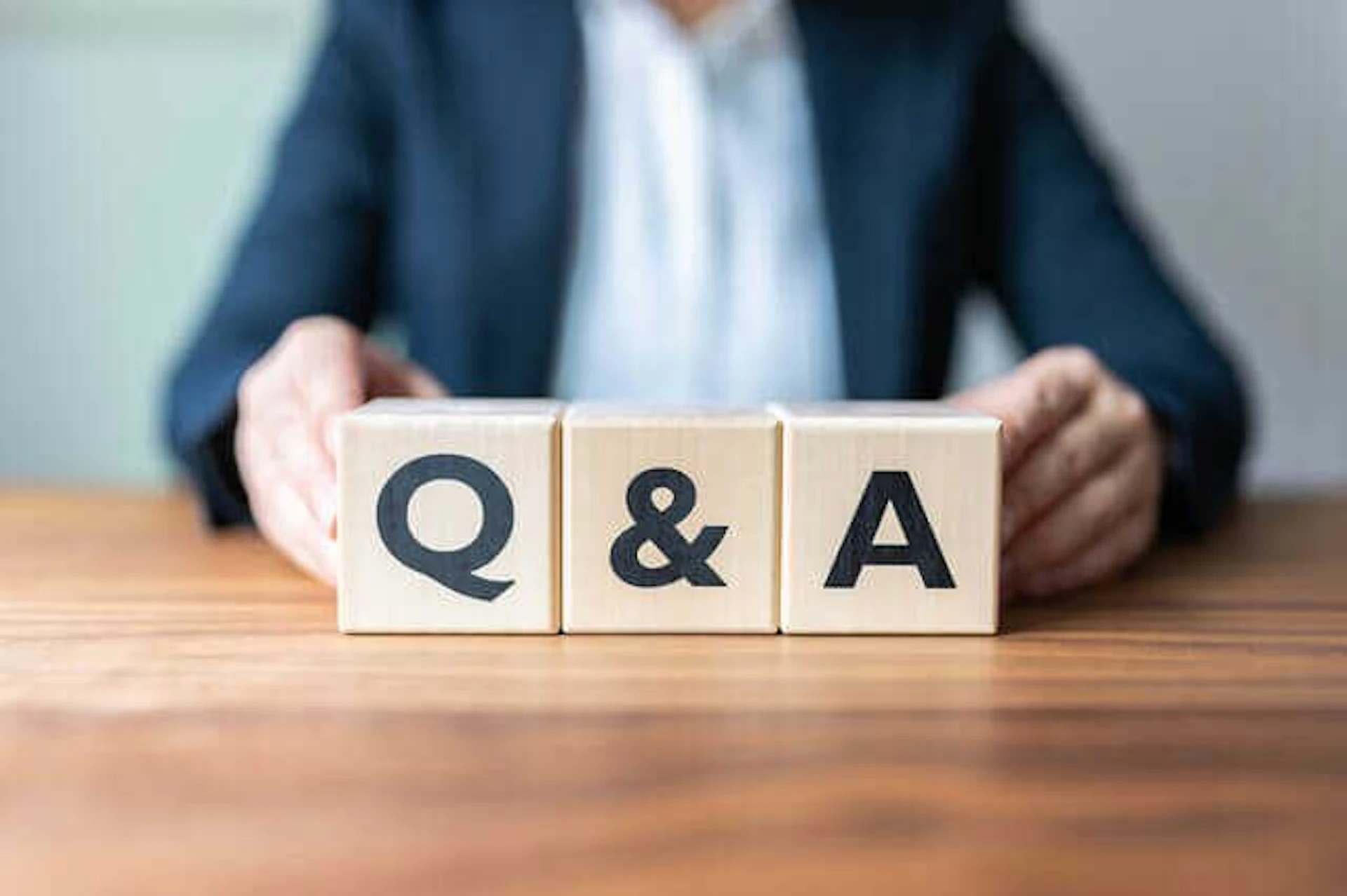 Q＆A表記の木製ブロックを机の上に置く男性