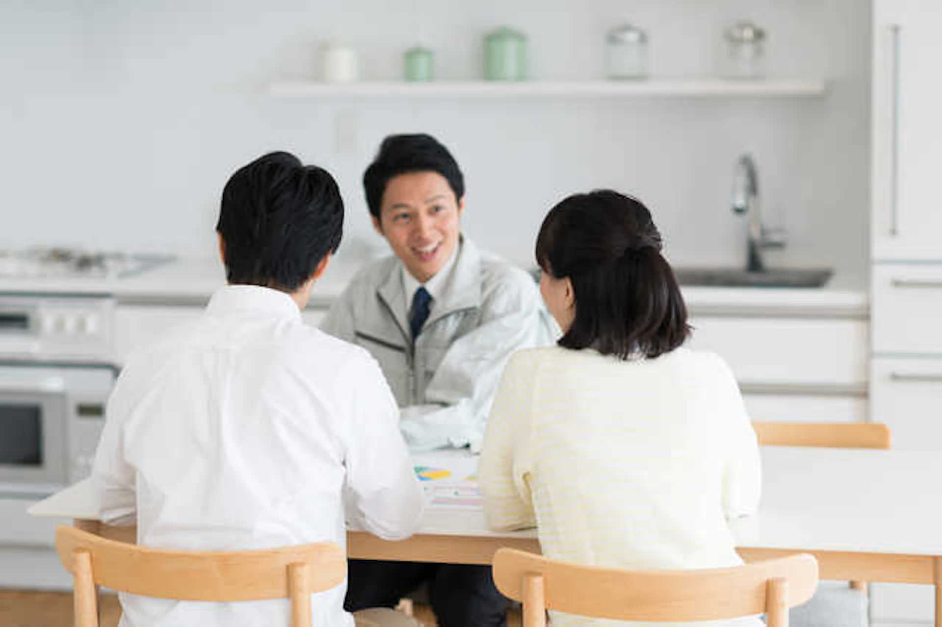 打ち合わせ中の夫婦とリフォーム業者(若い男性)