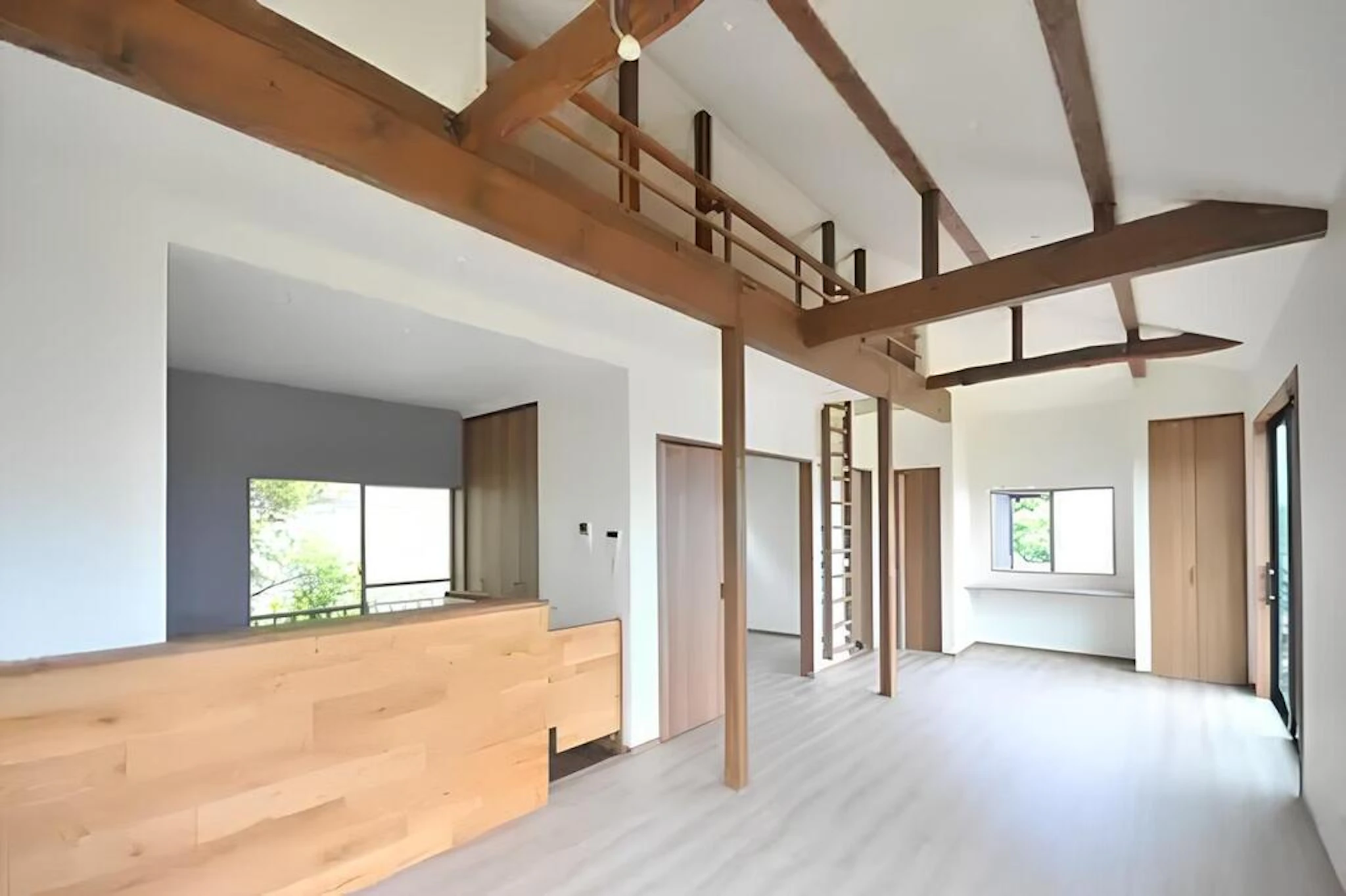 リノベーションした家の部屋 高い天井と光がたっぷりと入るリビング 白い壁や床に、ウッドの柱や家具がアクセントになっている