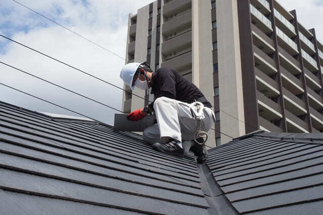 黒い屋根の上で点検する男性作業員