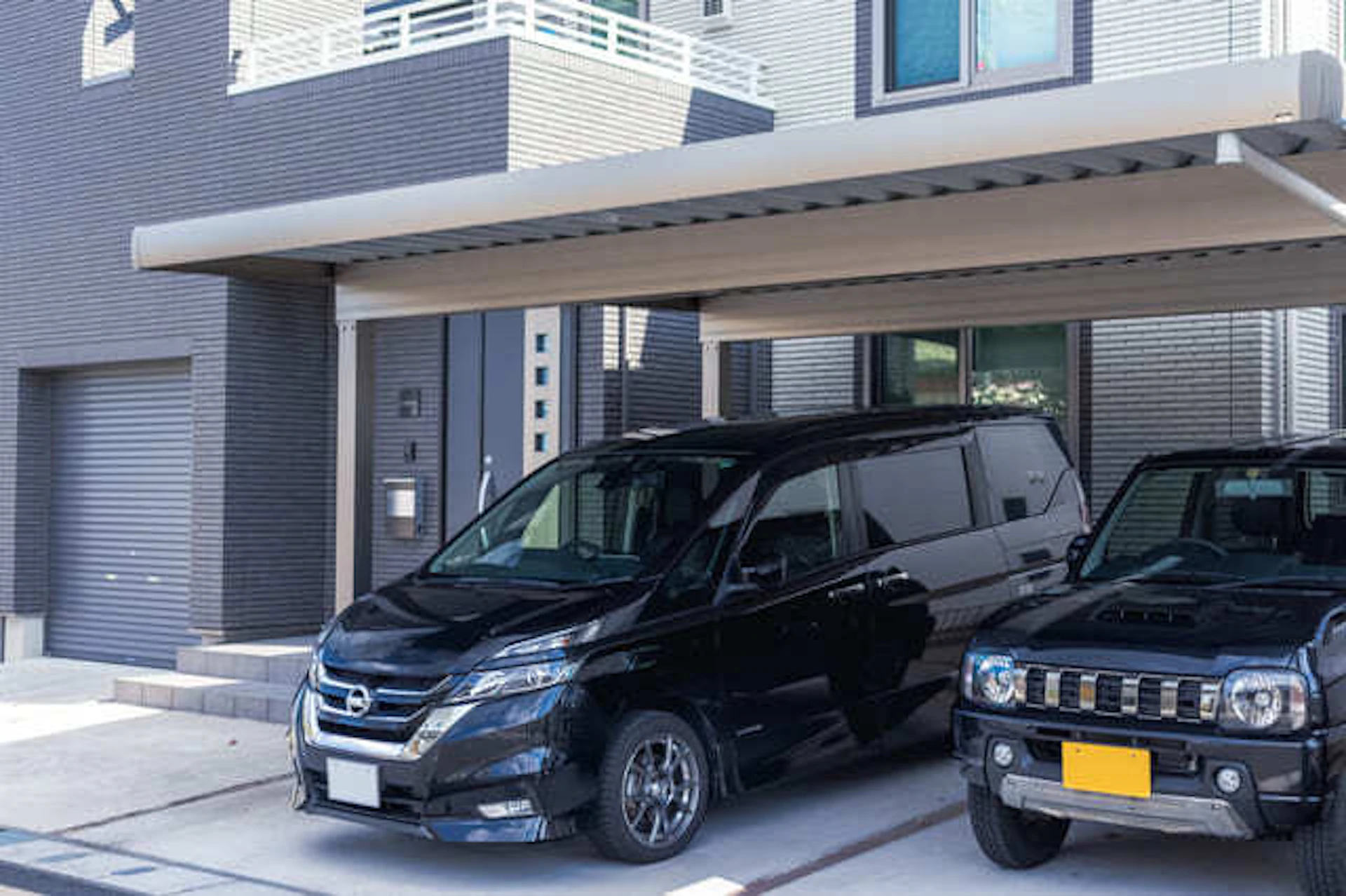 カーポートのある戸建て住宅/横並びに駐車している2台の黒い車