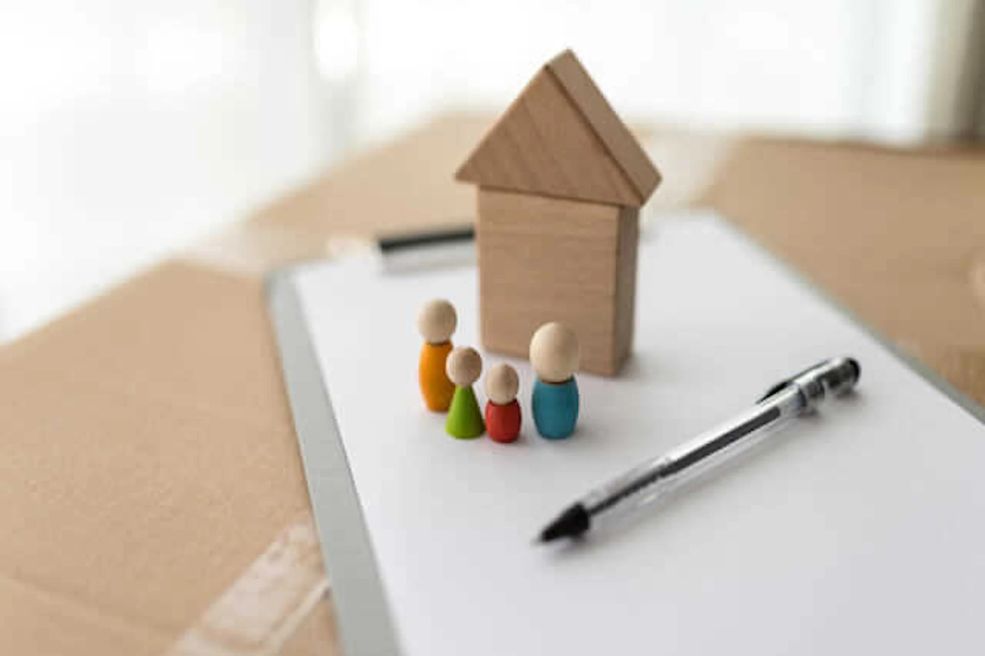 卓上に置かれた住宅のオブジェと紙とペン