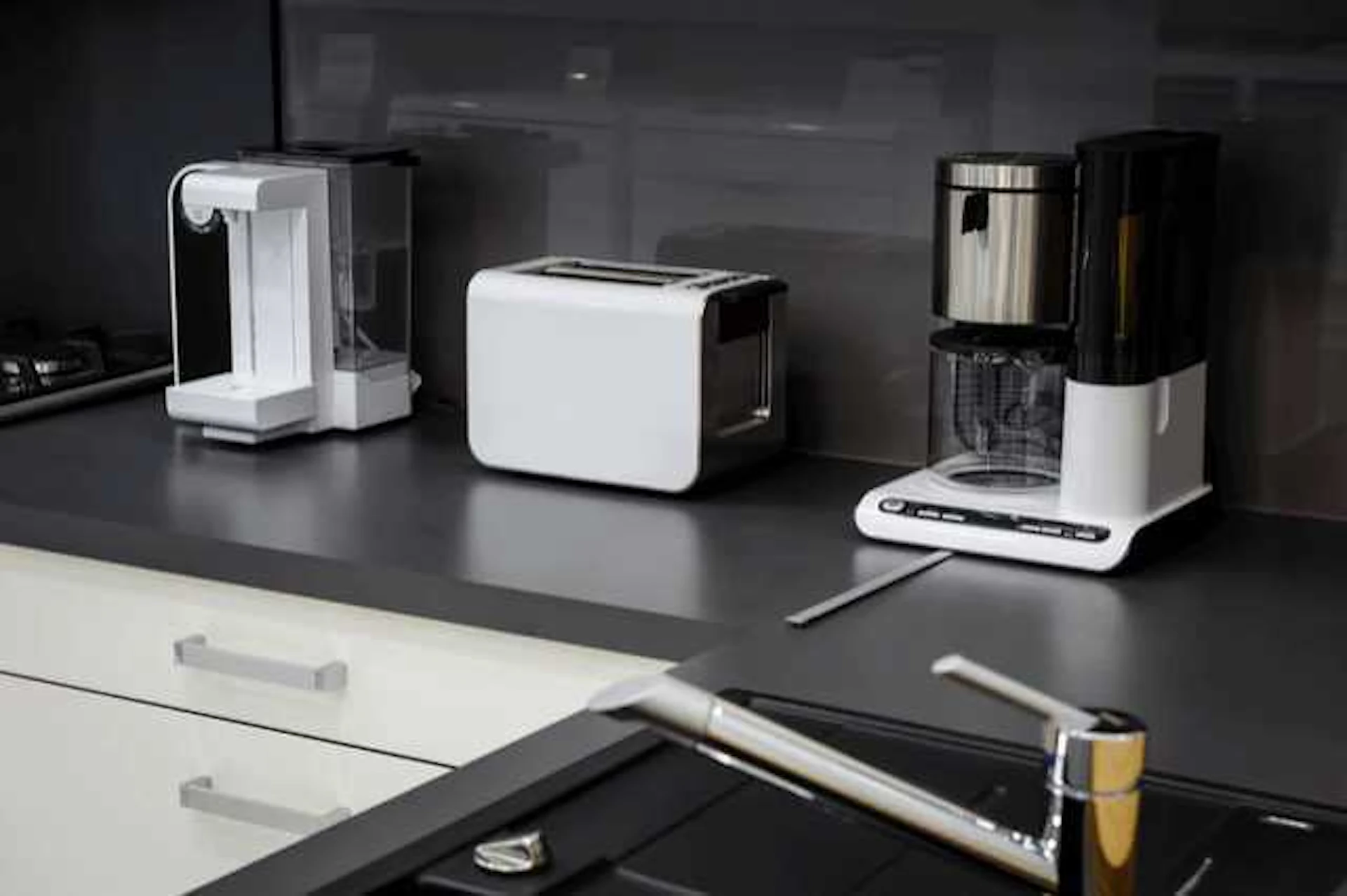 白黒のL型キッチンにトースターやコーヒーメーカーが並んでいる写真