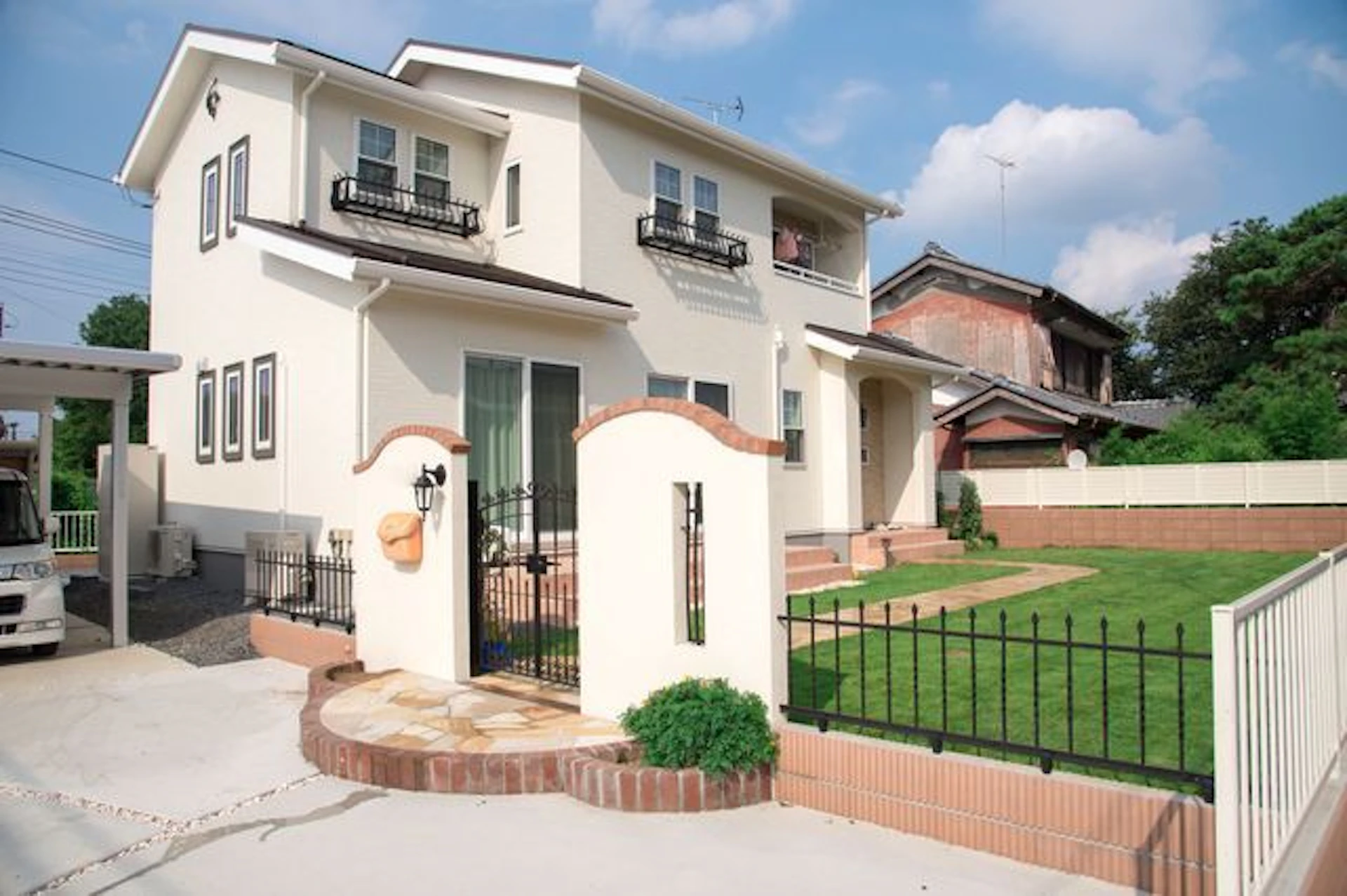 淡いベージュの壁の二階建ての家　芝生の庭