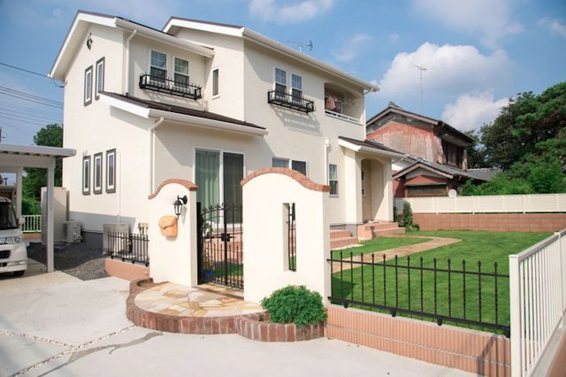 淡いベージュの壁の二階建ての家 芝生の庭