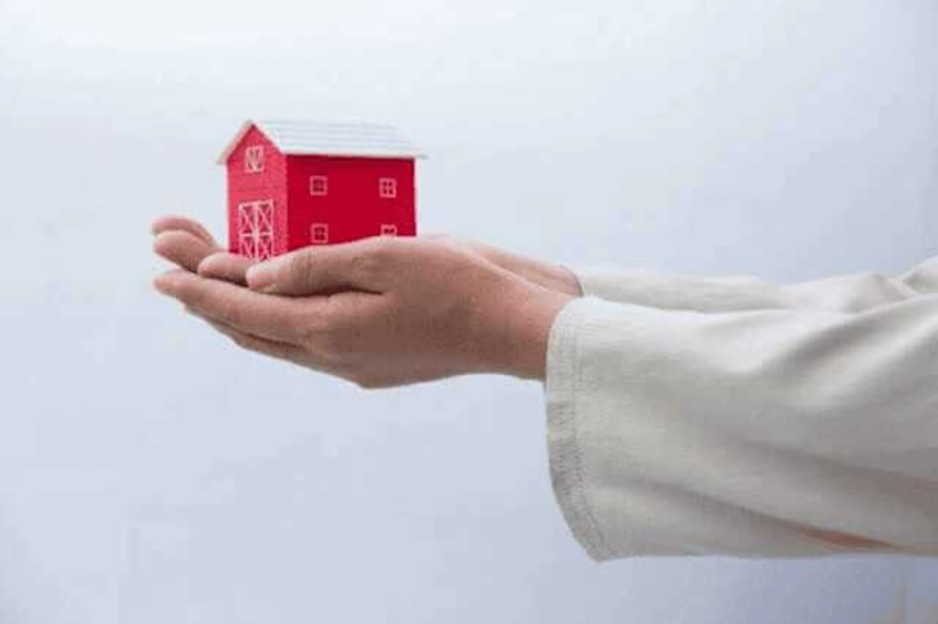 両手で赤い家のオブジェを持っている
