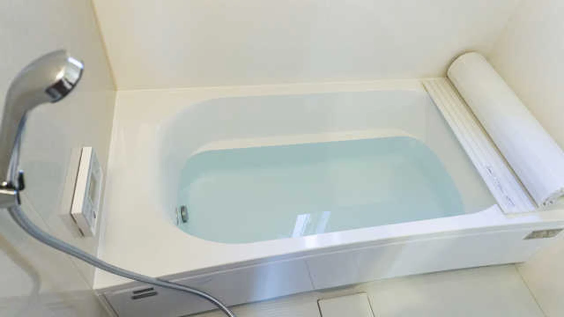 お湯のたまった白い浴槽と銀色のシャワー