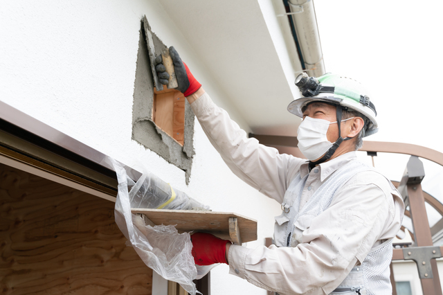 外壁に左官工事をする職人