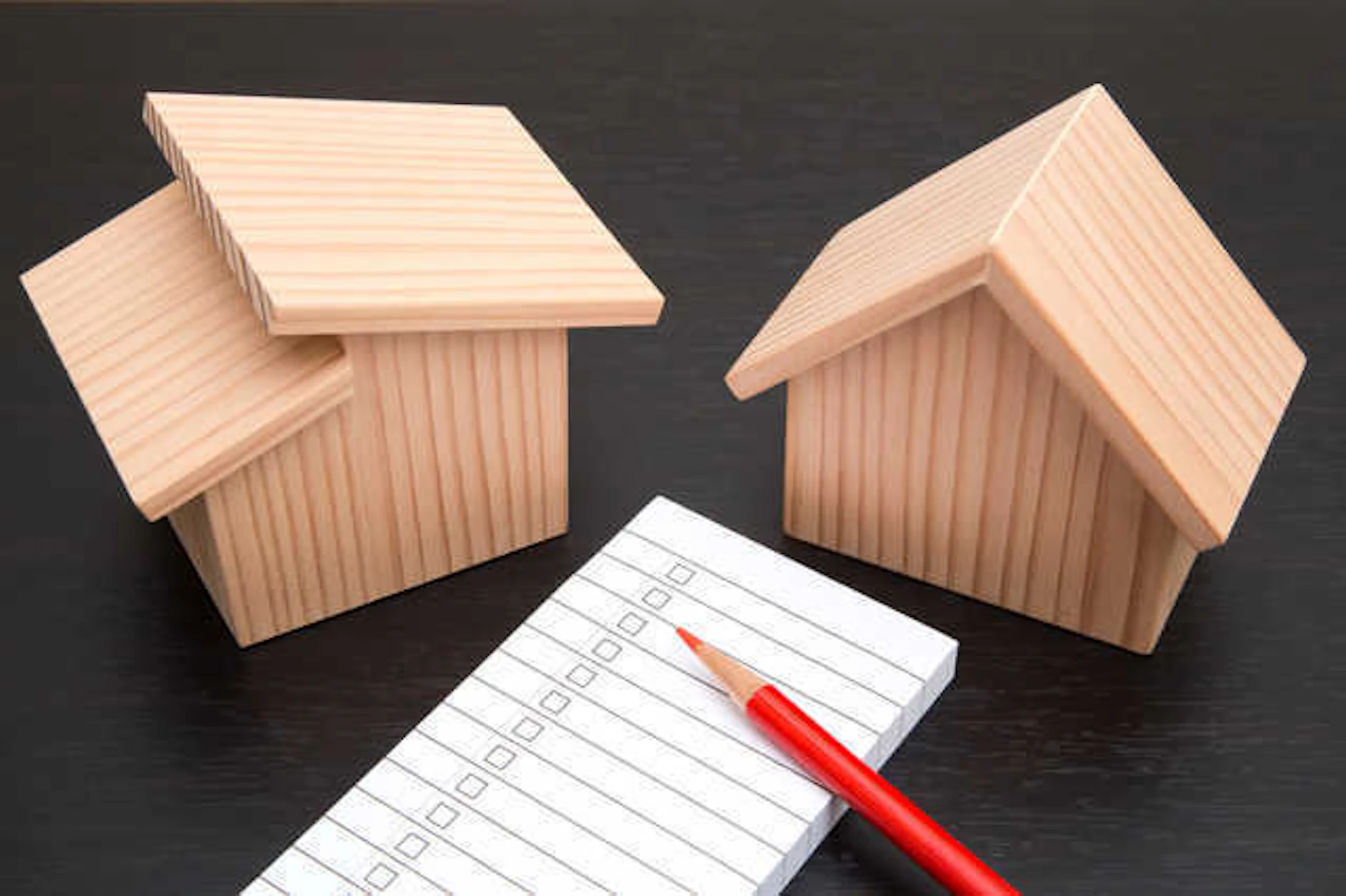 家の形の木のオブジェとメモ帳、赤鉛筆