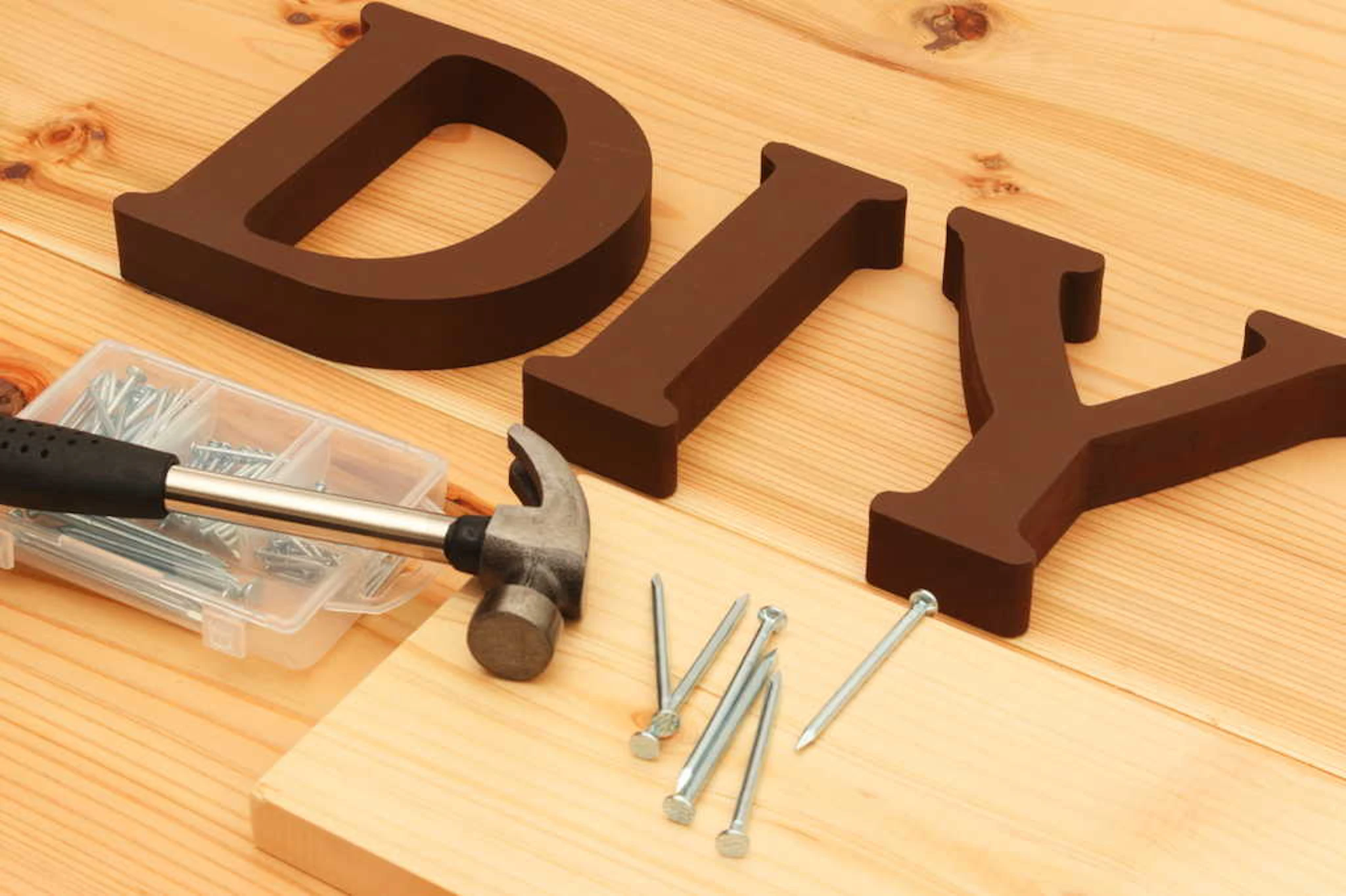 「DIY」の文字とトンカチ、ネジが置かれた木目の台