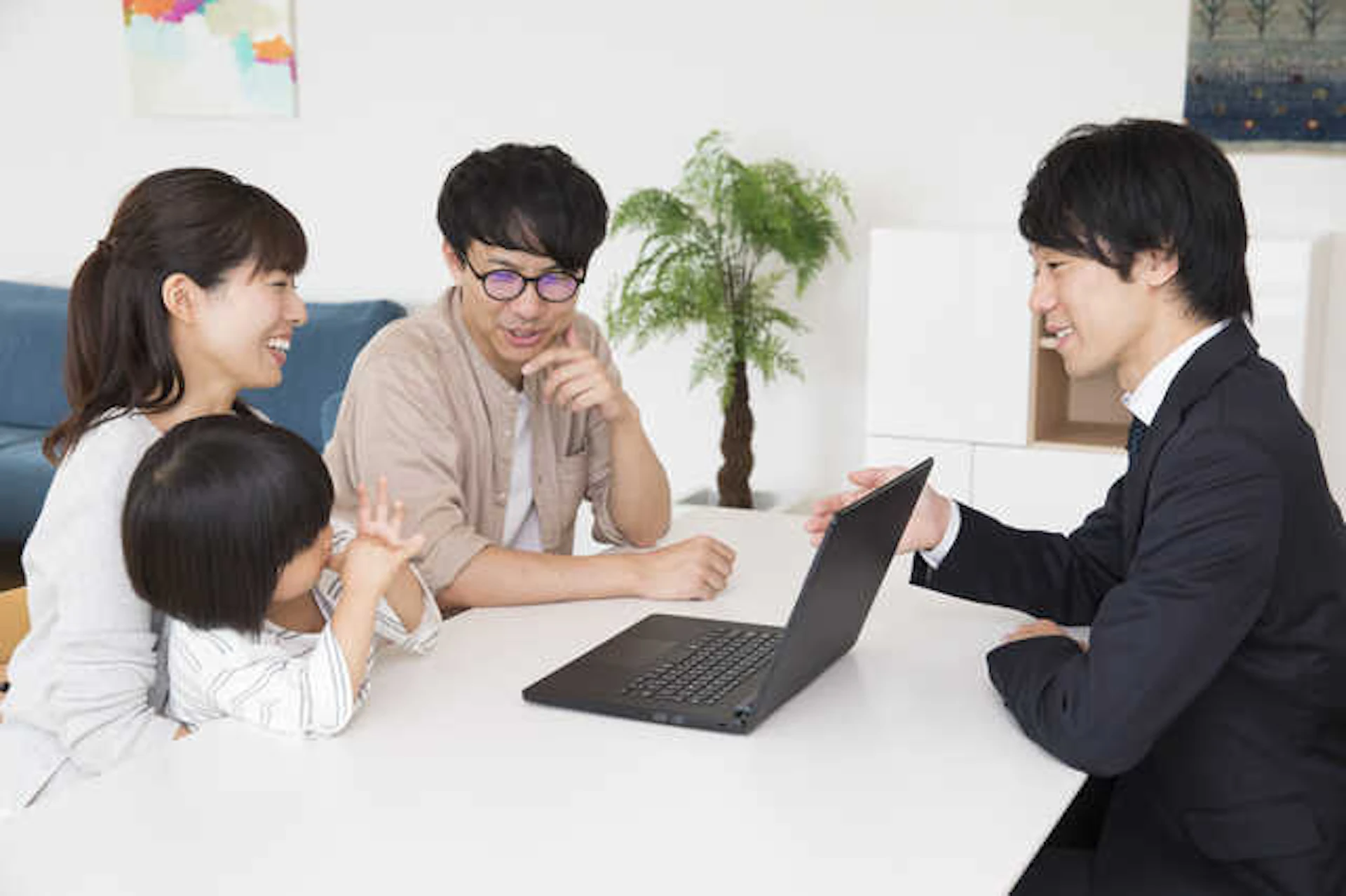 パソコンを見ながら相談している若い親子と、リフォーム業者の男性