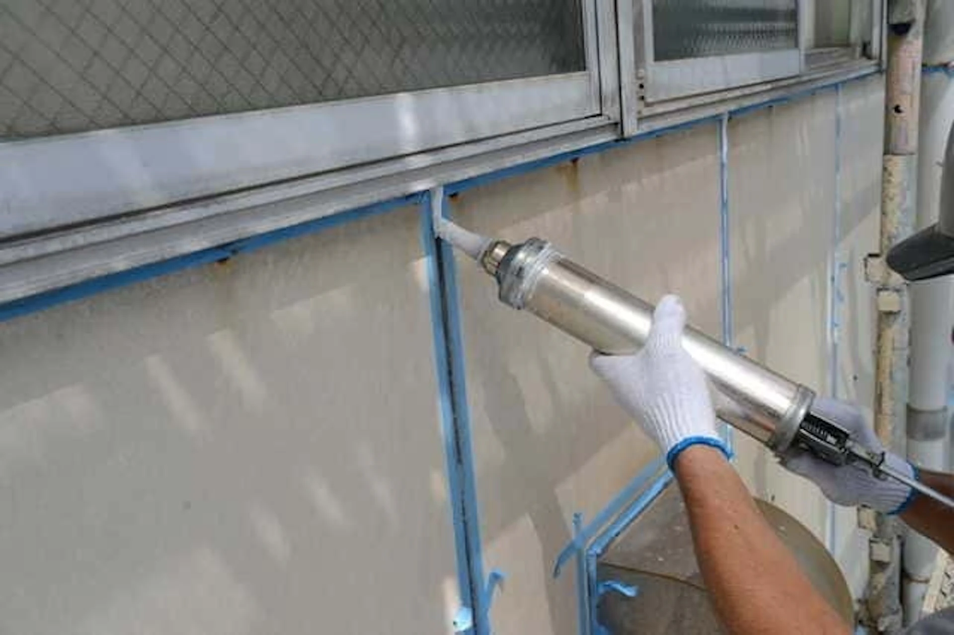 外壁のコーキング修理を進める男性作業員の手元