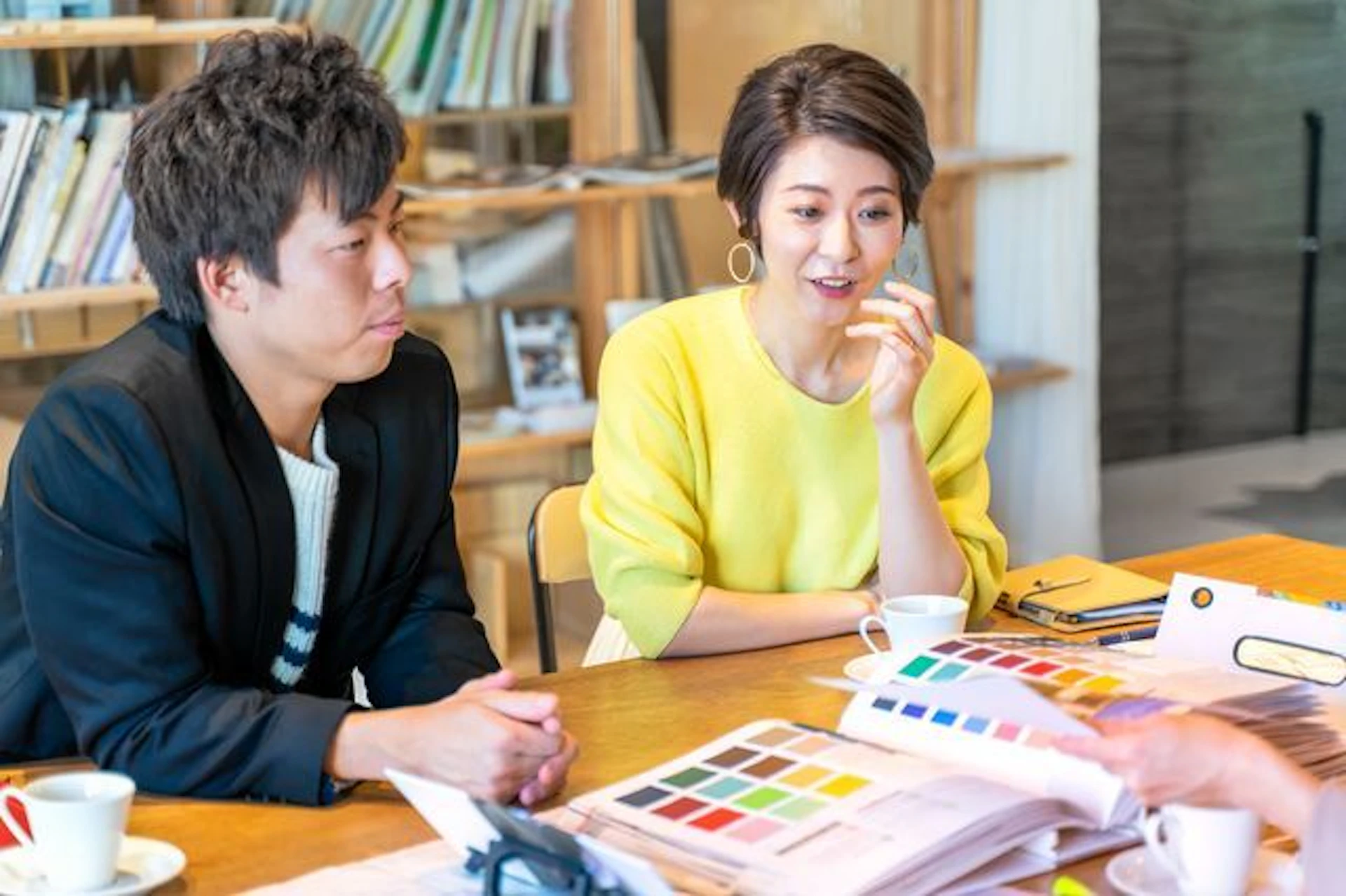 色見本帳を前に、外壁塗装の色を決めている男女