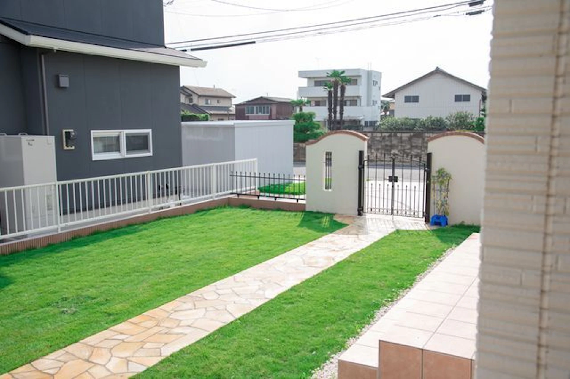 緑の芝生の真ん中にレンガ色の小道がある庭