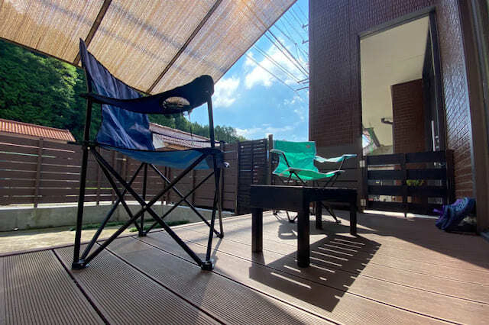 ウッドデッキにタープがかかり、チェアが二脚。リラックできる空間