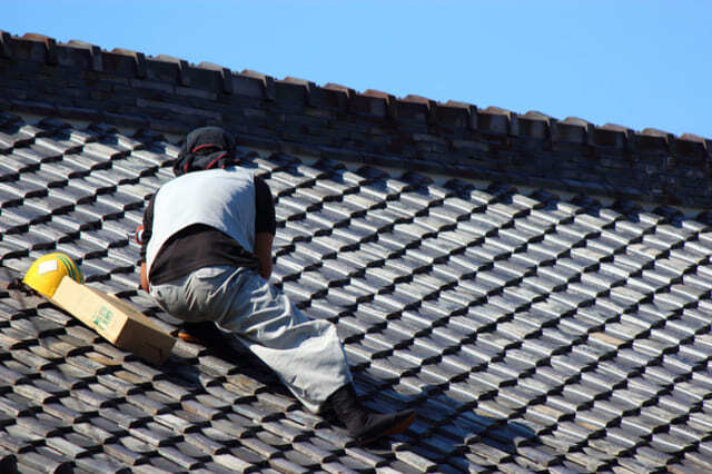 黒い屋根の上で工事を進める男性作業員