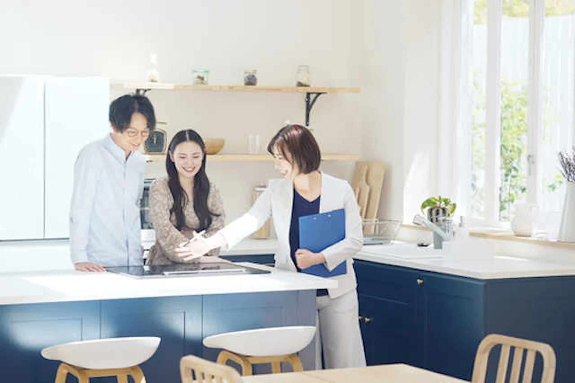 女性業者からシステムキッチンの説明を受ける若い夫婦