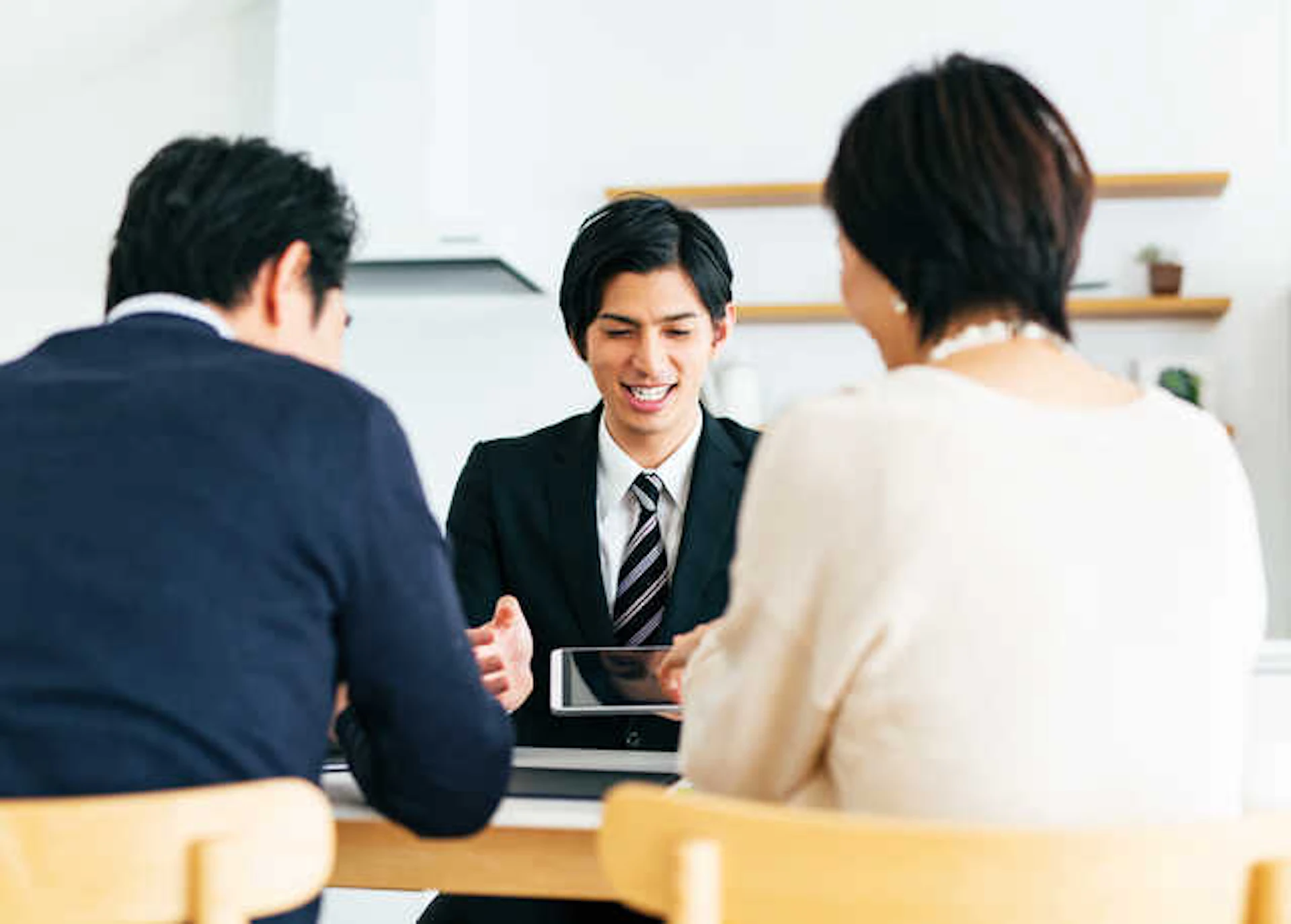 黒いスーツをきた業者の男性と話し合う夫婦